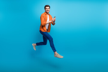 Aufkleber - Full length profile portrait of handsome excited guy use smart phone jumping rush empty space isolated on blue color background