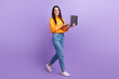 © deagreez - Full size photo of pleasant satisfied woman dressed oversize shirt hold laptop go to empty space isolated on violet color background