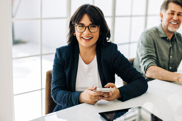 Wall Mural - Business woman holding a smart phone in a boardroom