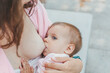 close-up baby sucking mom's breasts outdoors in the park, the concept of breastfeeding and motherhood