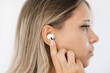 © Марина Демешко - White wireless headphones for sports, running, cycling, walking in the ears of a young caucasian blonde woman listening to music. A girl switches songs or changes the volume with her finger. Profile