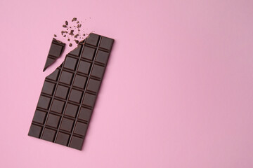 Wall Mural - Broken dark chocolate bar on pink background, flat lay. Space for text