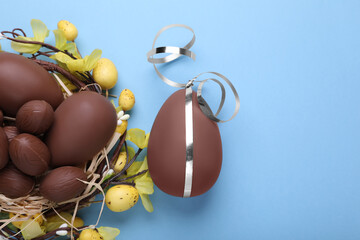 Wall Mural - Delicious chocolate eggs on light blue background, flat lay. Space for text