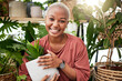 © Lategan/peopleimages.com - Happy, eco friendly and portrait of a woman with a plant in the nursery for a sustainable gift. Happiness, smile and African female person with green leaves in pot in greenhouse for gardening at home