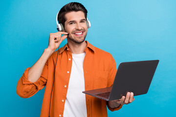 Fototapete - Portrait of positive handsome guy helpdesk operator hand touch headset microphone use netbook isolated on blue color background