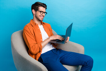 Fototapete - Portrait of positive intelligent guy sitting comfy chair use wireless netbook coworking isolated on blue color background