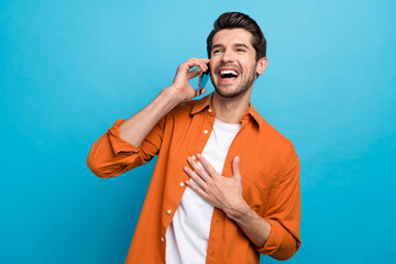 Fototapete - Portrait of overjoyed crazy man speak chatting telephone hand chest laughing isolated on blue color background