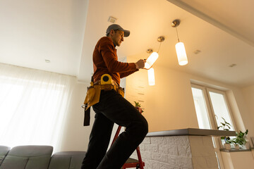 Electrician man working on exterior light, install LED replacement lamp at home. Maintenance concept.