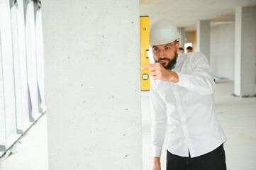 Wall Mural - Young attractive arabic industrial engineer in hard hat. Professional and industry, builder architect job, worker checking work at plant indoor