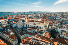 Aerial Drone View Of Carmo Church And Surrounding Historic Neighbourhood In Chiado, With Tagus River And 25 April Bridge Visible, Lisbon, Portugal