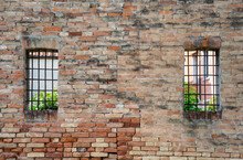 Old Red Brick Wall With Two Rusted Iron Grill Windows.
