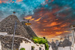 Alberobello Trulli, Puglia, Italy. General view of traditional and touristic Trulli houses, amazing sky at sunset in the background.