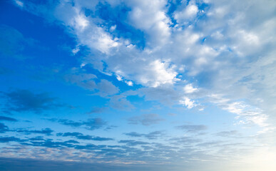 Wall Mural - blue sky with puffy white clouds at sunrise or sunset shot at 28 mm focal length