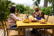 © wavebreak3 - Happy biracial parents, son and daughter praying before meal, sitting at table in sunny garden