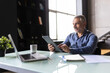 © F8  \ Suport Ukraine - Thoughtful smiling mature businessman with tablet pc sitting in office