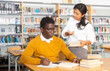 © JackF - Young woman library staff helping man gaining new skills giving him books