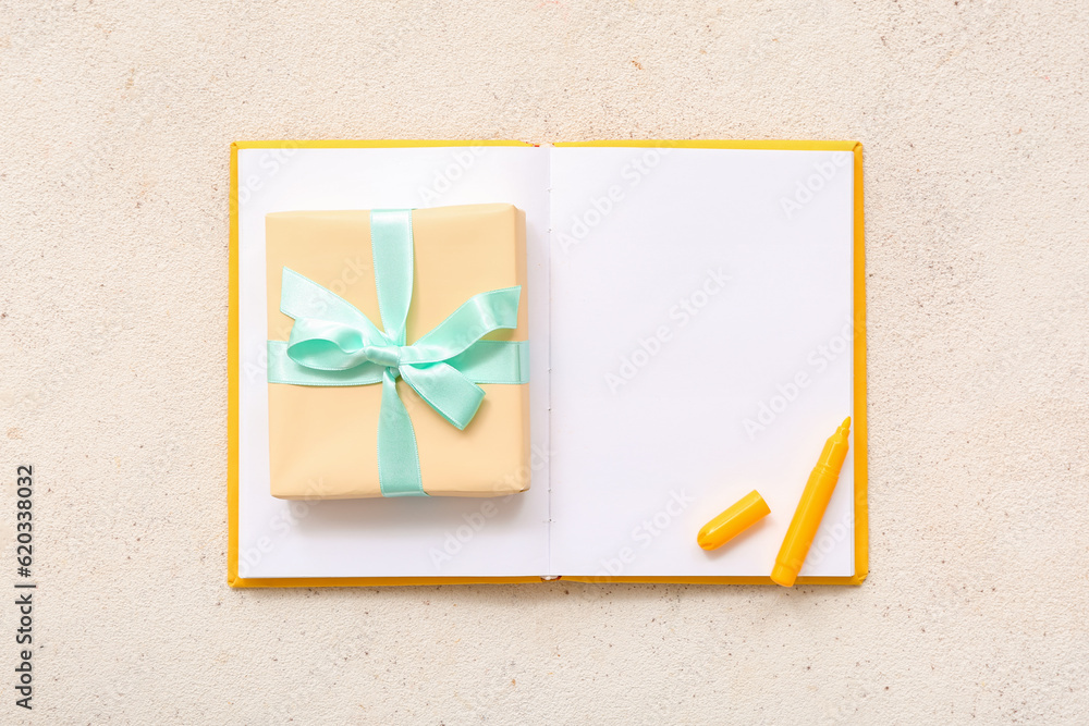 Gift box with open notebook and marker on grunge white background