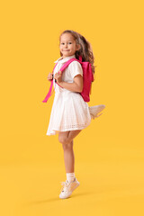 Jumping little schoolgirl on yellow background