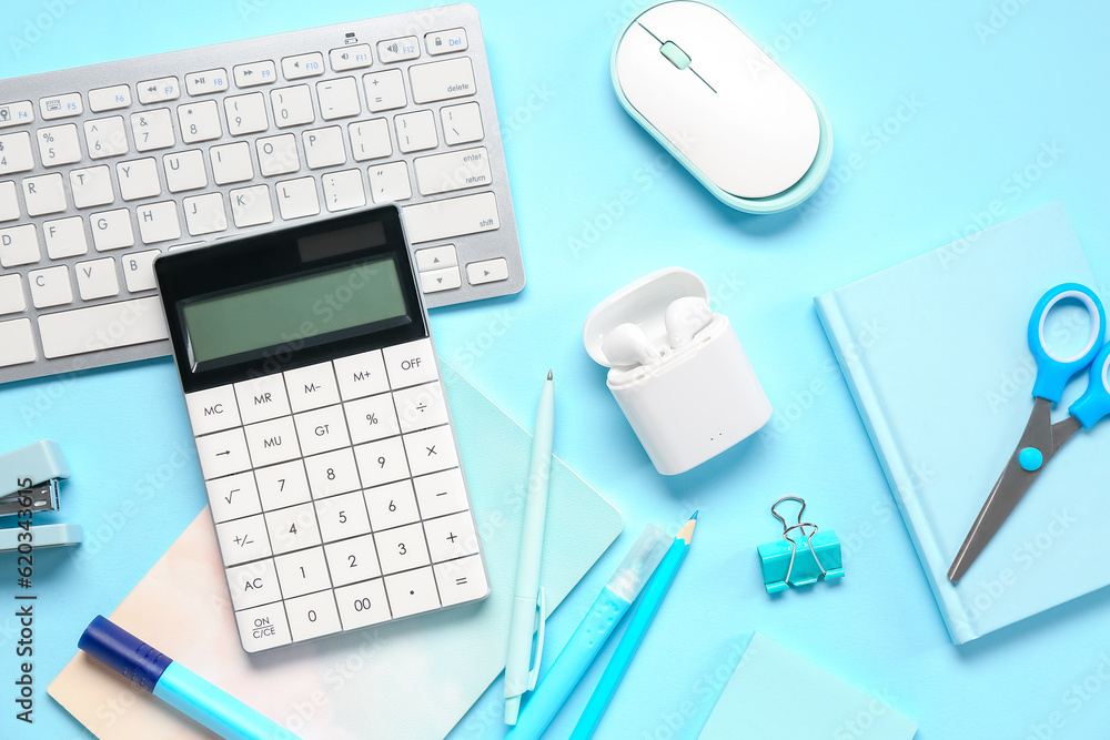 Calculator with stationery, computer keyboard and mouse on blue background
