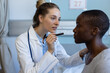 © Wavebreak Media - Diverse female doctor and patient examining patient, using flashlight at hospital