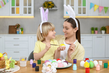 Sticker - Mother and her cute son painting Easter eggs at table in kitchen