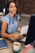 © Wavebreak Media - Portrait of happy caucasian businesswoman using phone headset and using computer, smiling at office