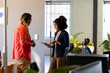 © Wavebreak Media - Two diverse casual business colleagues with tablet standing in office talking, copy space