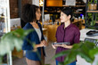 © Wavebreak Media - Two diverse female casual business colleagues with tablet standing in office talking