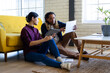 © Wavebreak Media - Two diverse casual business colleagues with tablet and document sitting on floor in office talking