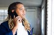 © Wavebreak Media - Biracial casual businessman with dreadlocks talking on smartphone standing at window in sunny office