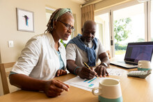 Senior African American Couple Sitting At Table Using Laptop And Paying Bills At Home