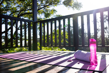 Wall Mural - Balcony of log cabin with bottle of water, towel, earphones and mat on sunny day