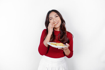 Wall Mural - Image of smiling young Asian girl eating french fries isolated on white background