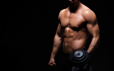 strong, fit and sporty bodybuilder man with a dumbbell over black background