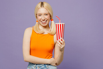 Wall Mural - Young blonde woman wear orange tank shirt casual clothes hold in hands cup of soda pop cola fizzy water look camera isolated on plain pastel light purple background studio portrait. Lifestyle concept.