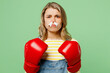 Sick unhealthy ill allergic woman has red watery eyes runny stuffy sore nose with tissue suffer from allergy trigger symptoms hay fever wears boxing gloves isolated on plain green background studio.