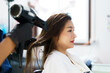 Happy cheerful Asian beautiful woman having a haircut and styling in professional hairdresser - salon shop, female hairdresser using a hair dryer bowling female customer hair.