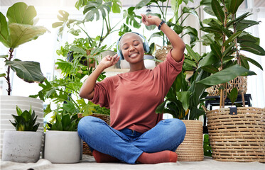 Wall Mural - Music, dance or freedom with a black woman in her home by plants while listening to an audio playlist. Headphones, flare and subscription service with a carefree young person streaming in a house