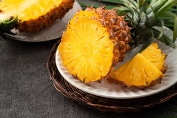 Wall Mural - Fresh cut sliced pineapple in a plate over dark gray table background.