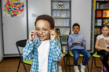 Wall Mural - Schoolboy standing in middle of classroom and answering question in front of classmates and teacher.