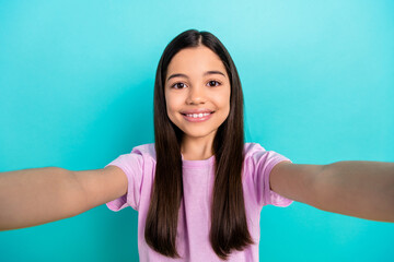 Wall Mural - Selfie photo of young little schoolgirl first blog video recording her smile wear pink stylish t-shirt isolated on cyan color background