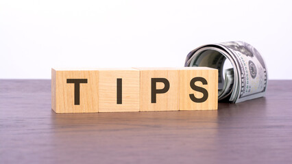 Poster - the word TIPS on wood cubes and banknotes on the background, business and finance concept