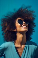 Poster - Woman with curly hair wearing sunglasses and blue shirt with her hair blowing in the wind. Generative AI.