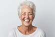 Smiling senior woman looking at the camera while standing against white background