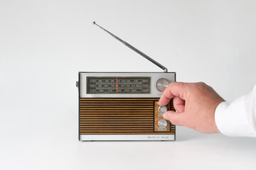 A man's hand twists the wave setting. Authentic radio from the 70s. Isolated on white background. Traces of time and scuffs on the case