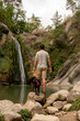 © Alba Vitta/Stocksy - Portrait of happy man and dog in nature by waterfall
