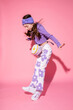© Asya Molochkova/Stocksy - Fashionable girl jumping on pink background