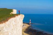 Tourist Stands On Top Of The Cliff Overlooking Beachy Head Lighthouse, Seven Sisters Chalk Cliffs, South Downs National Park, East Sussex, England