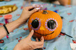 © Ezequiel Giménez/Stocksy - Crop woman decorating pumpkin with stickers