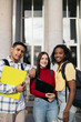 © Pedro Merino/Stocksy - Portrait of three young students with folders and backpacks